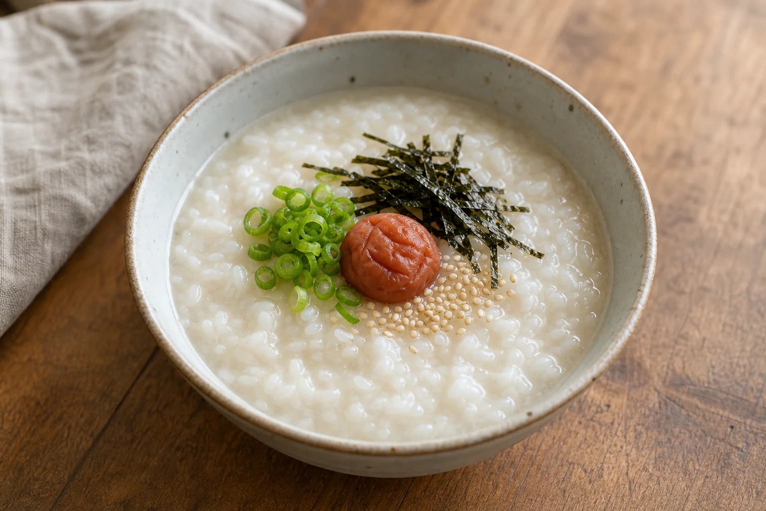 Japanese okayu with very soft short-grain rice, umeboshi, scallion, sesame, and nori strips.